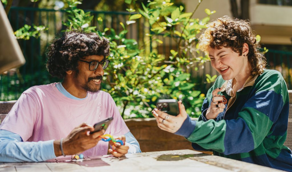 two people smiling on their phones outside
