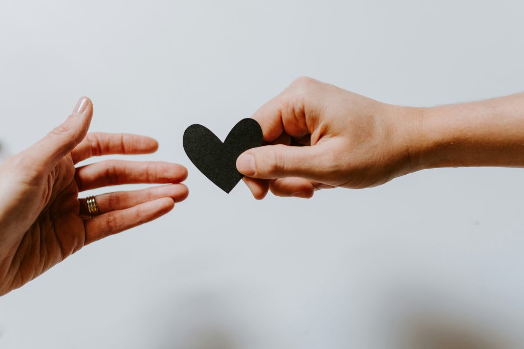 Photograph of two hands holding a paper heart