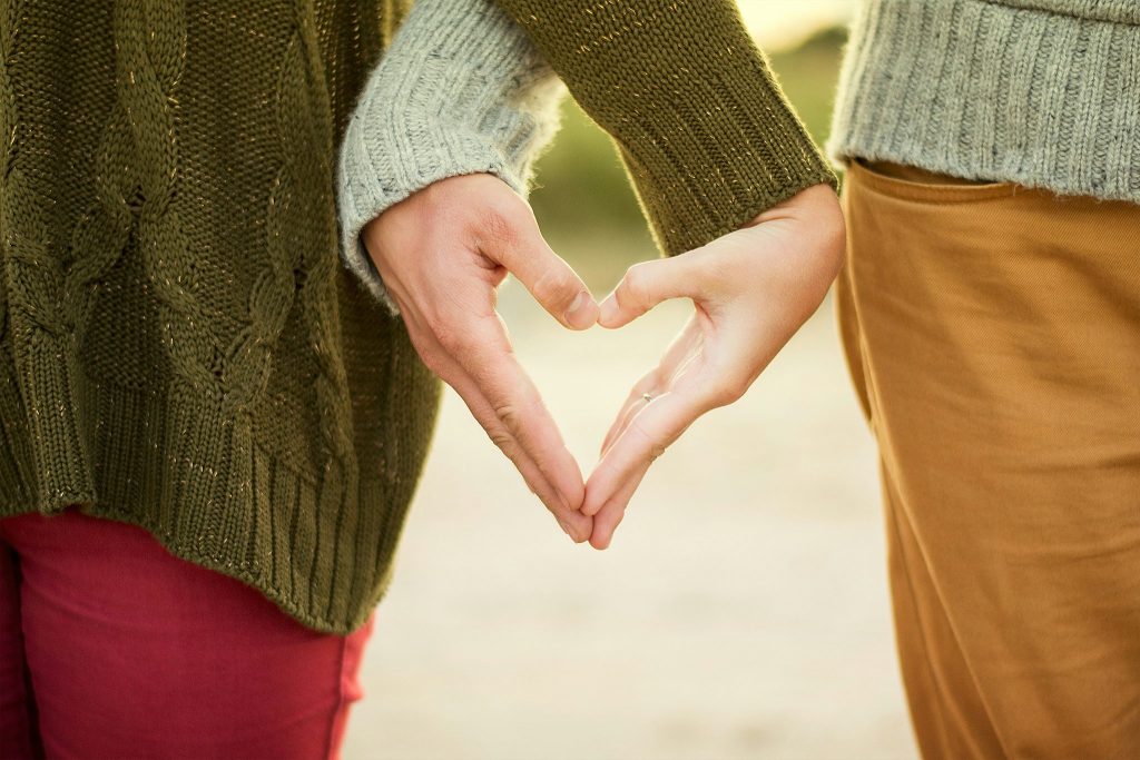 two people holding hands making a heart shape