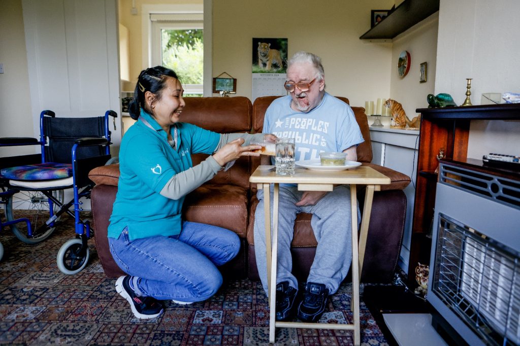 Old man eating a meal with a support worker